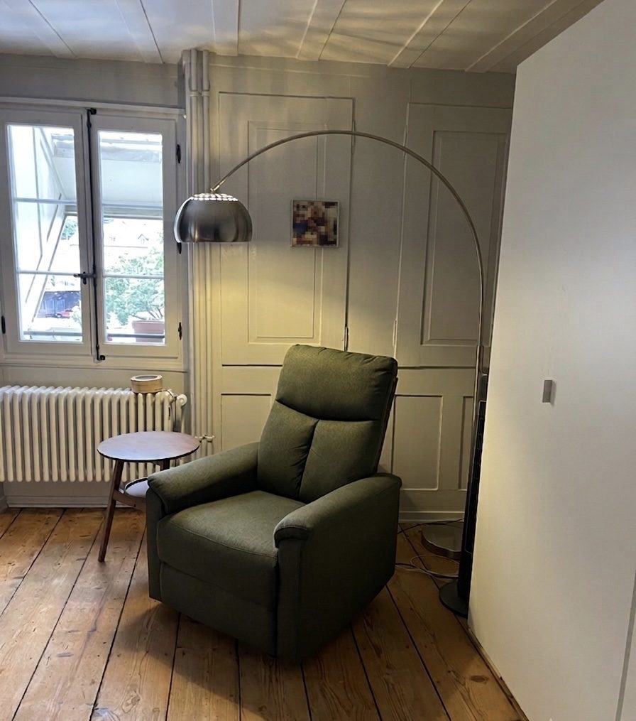 Gemütlicher grüner Sessel mit Bogenlampe im aufgeräumten Schlafzimmer